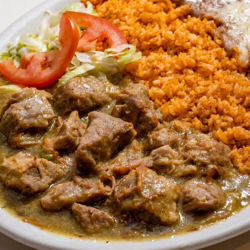 Pork chile verde with rice, refried beans, and a side salad on a white plate.